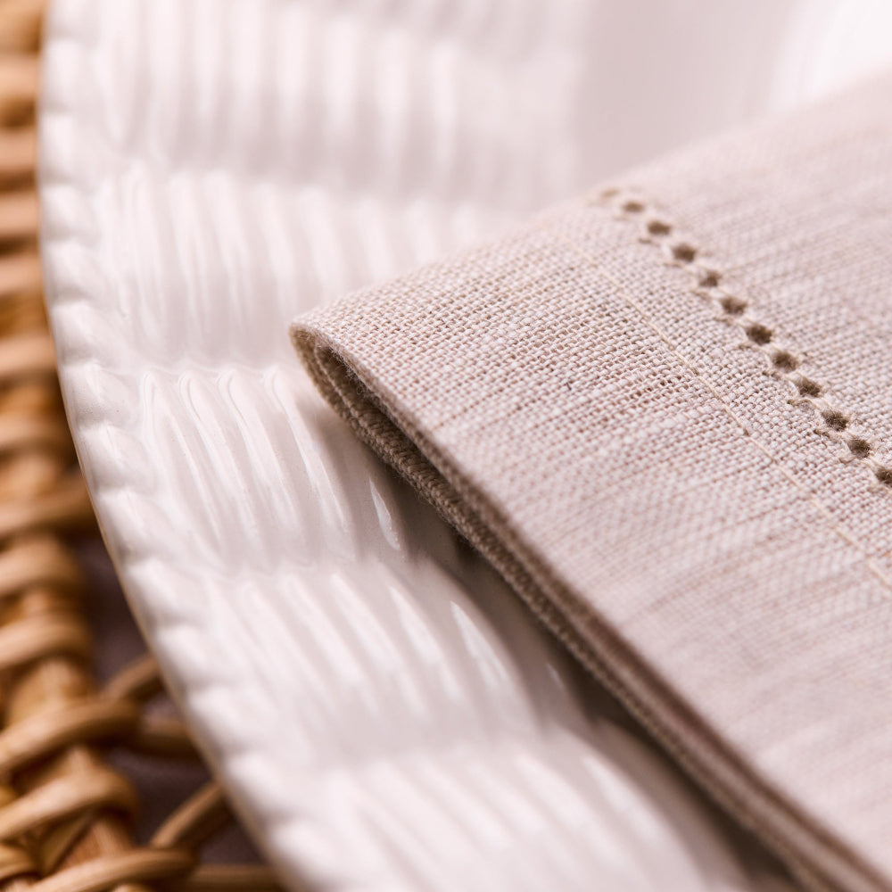 Close-up of beige linen napkins with a textured edge on a white background