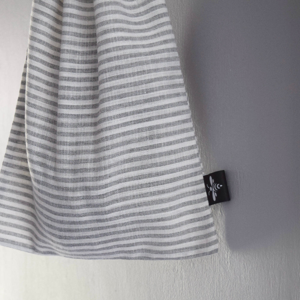 Striped linen bread bag with a brand tag on a light grey background