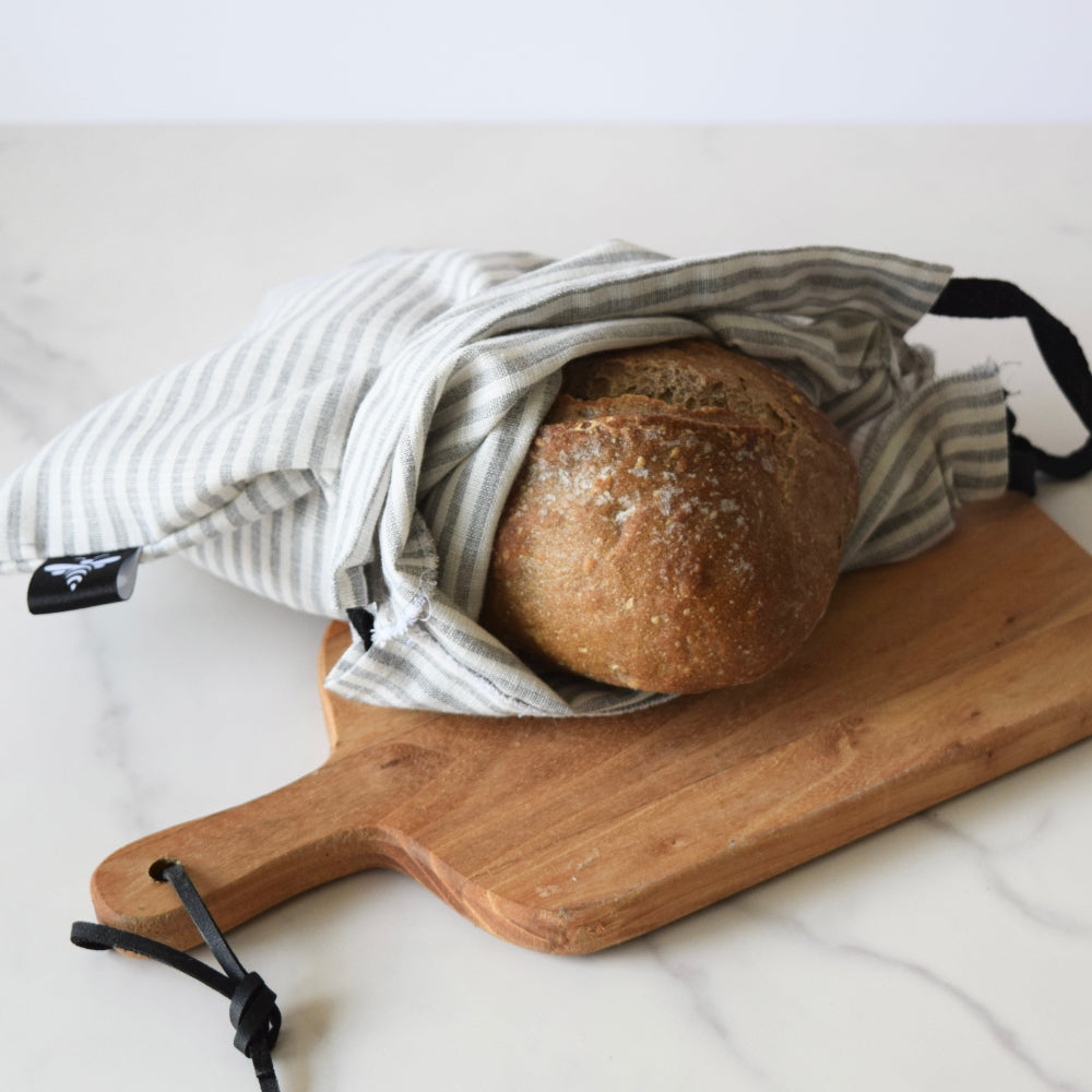 Loaf of bread in a reusable bag on a wooden cutting board