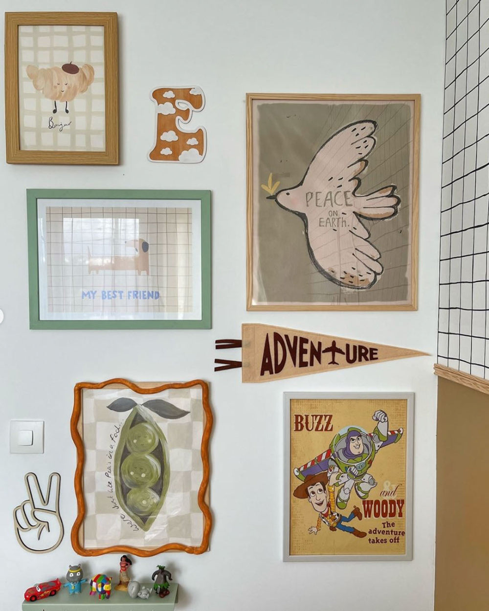 Wall with various framed pictures and decorations including a peace sign and cartoon characters.