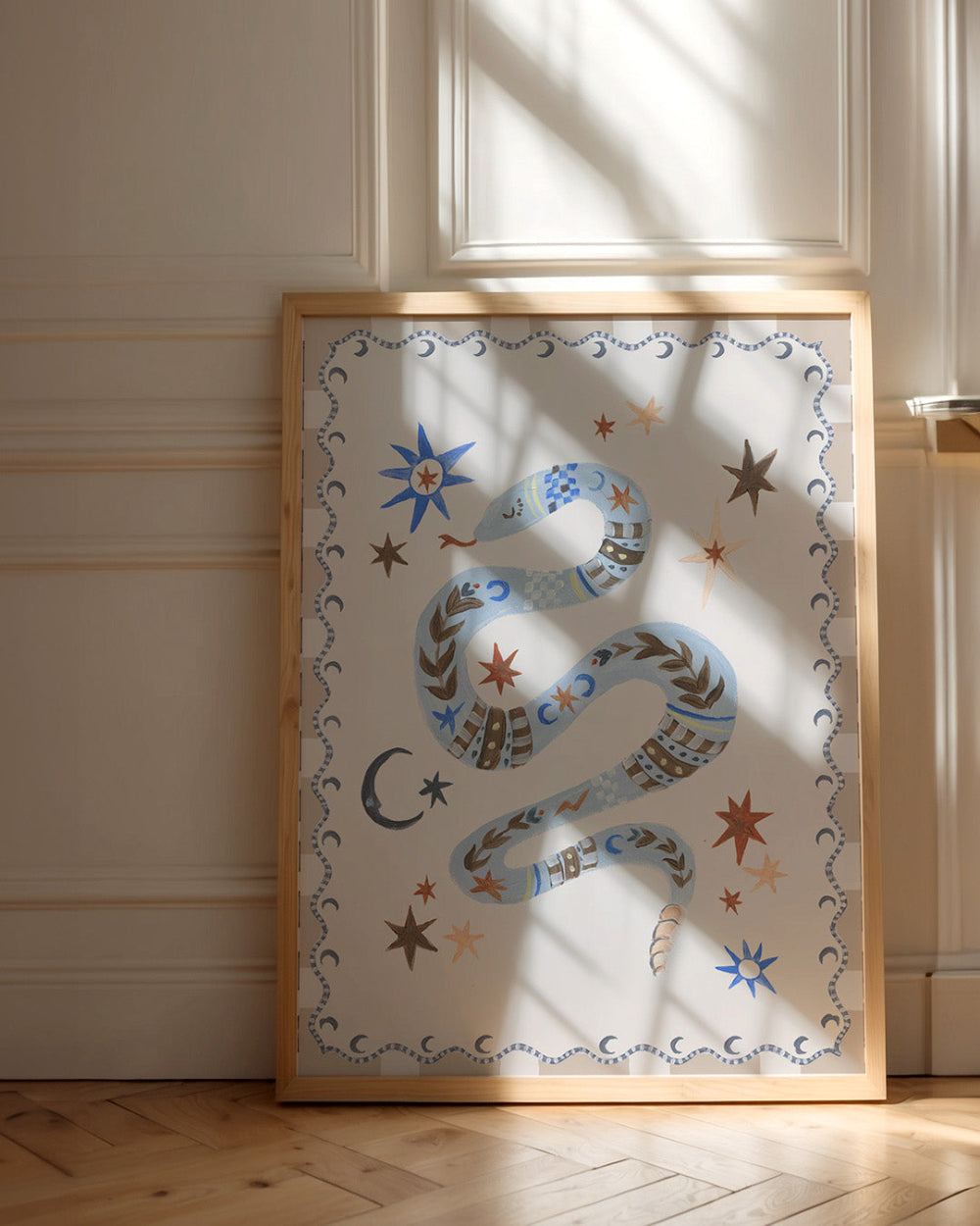 Decorative wall art with a snake design in a wooden frame on a light-colored wall.