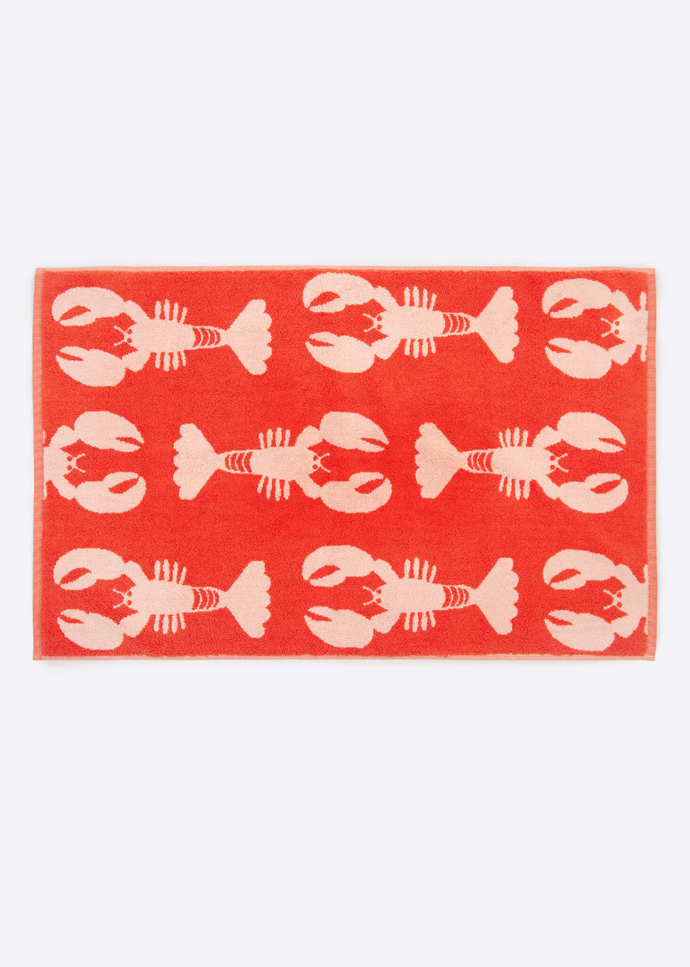 Red bath mat with white lobster pattern on a white background