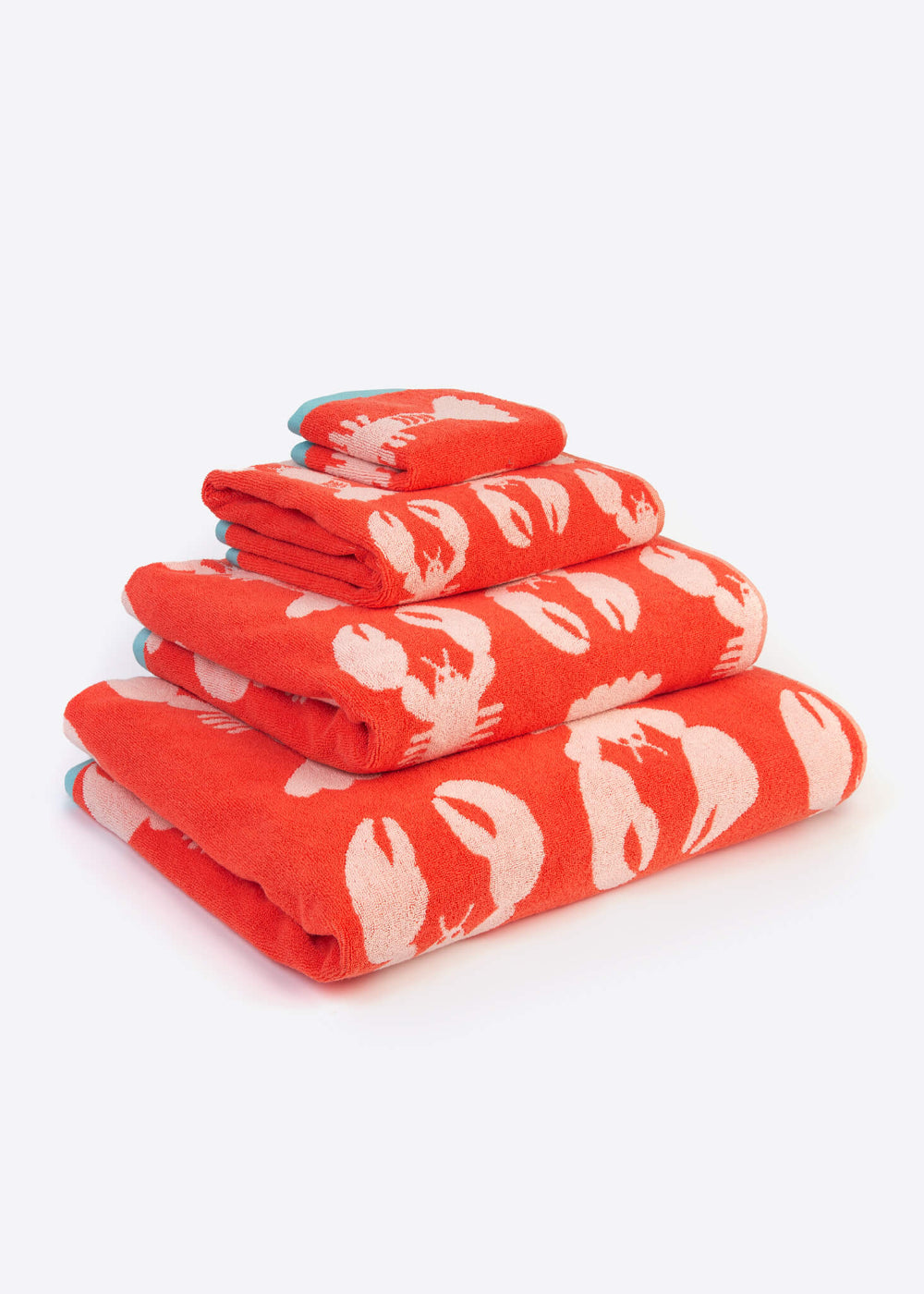 Stack of red towels with white lobster pattern on a white background