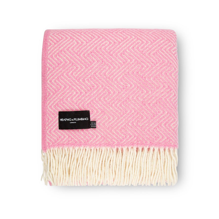 Pink woven blanket with a brand label on a white background