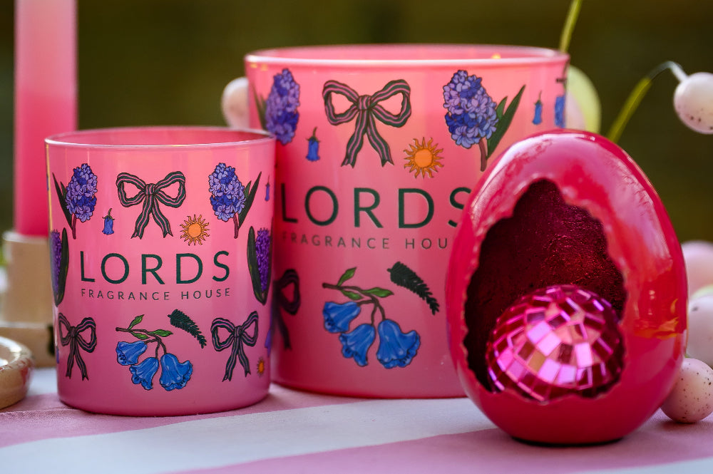 Two pink candles with floral designs and 'LORDS' branding on a pink surface.