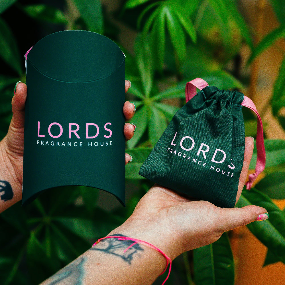 Two green packaging items from Lords Fragrance House held against a leafy background.