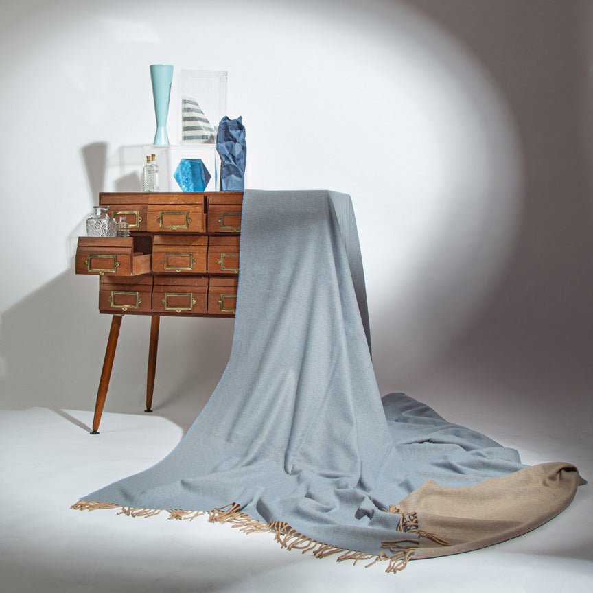 Wooden side table with decorative items and a light blue throw blanket draped over it.