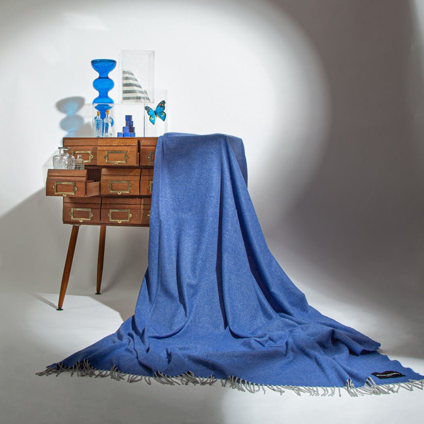 Blue blanket draped over a wooden cabinet with decorative items on a white background