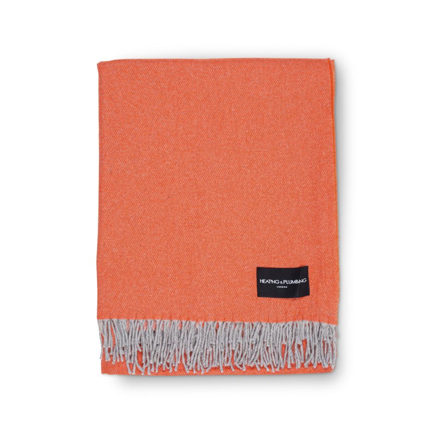 Orange blanket with gray fringes and a brand label on a white background