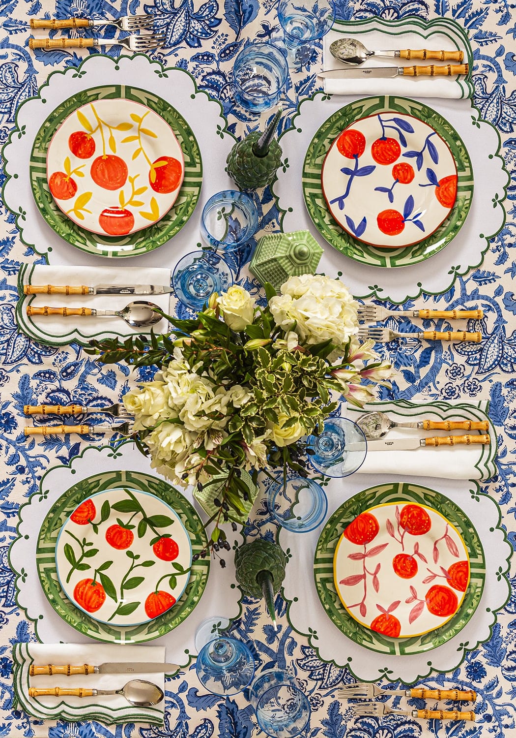 Decorative table setting with floral centerpieces and patterned plates on a blue and white tablecloth.