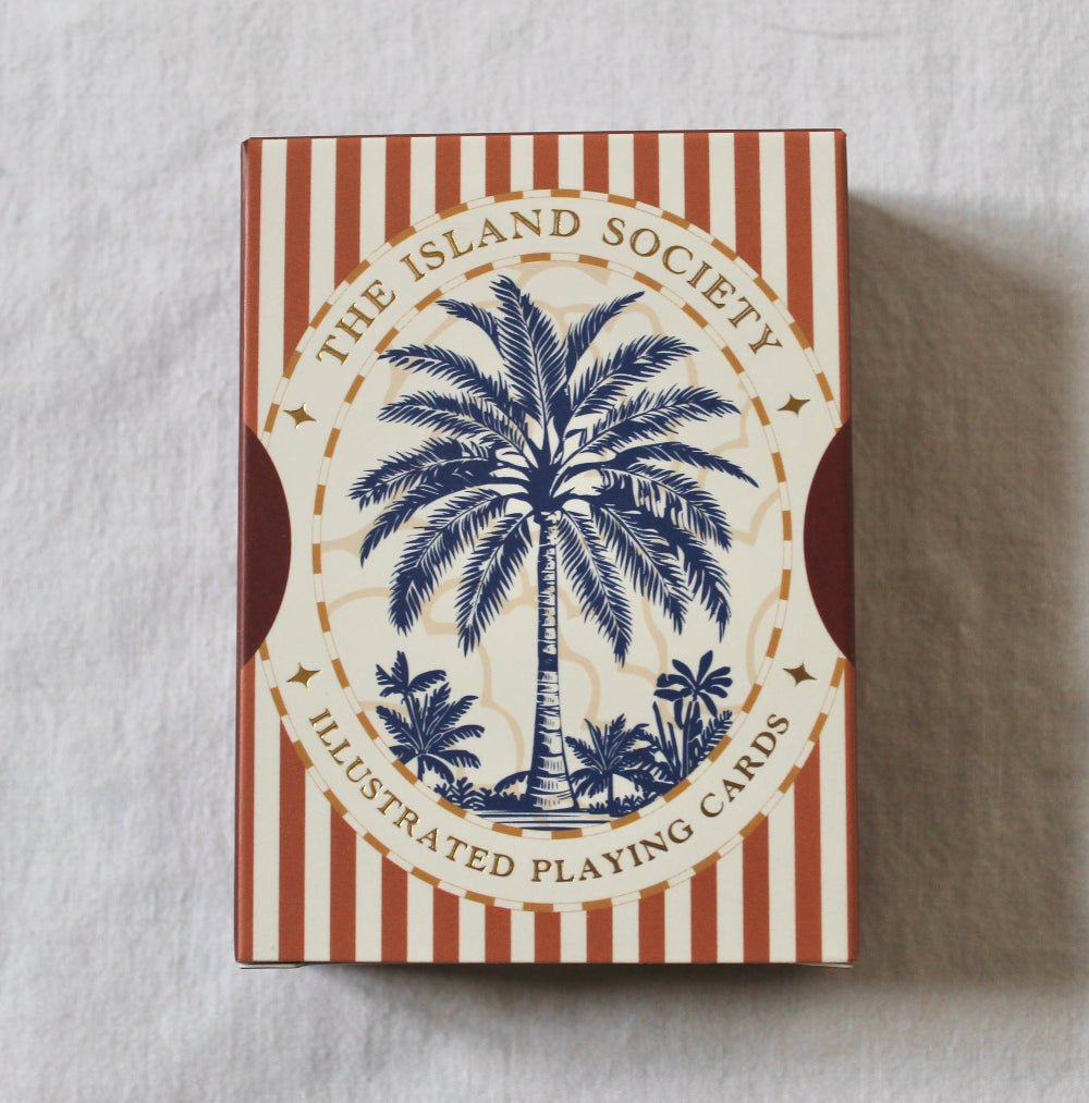 Red playing cards by The Island Society featuring decorative illustrated designs.