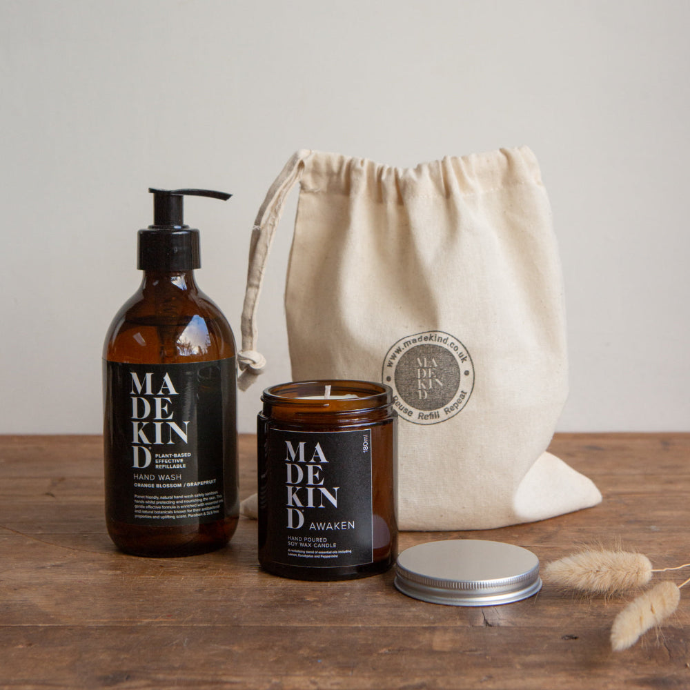 Madekind handwash product set with bottle, candle, and drawstring bag on a wooden surface.