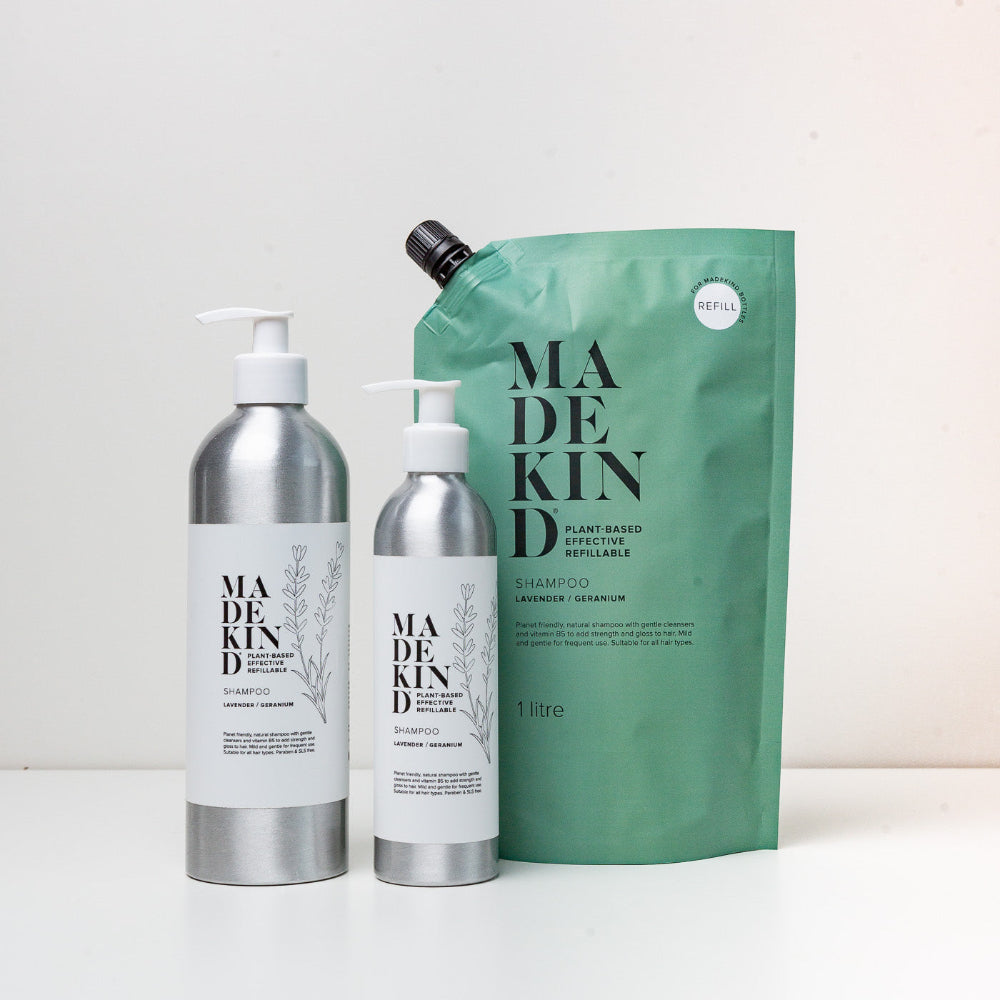 Made Kind shampoo and conditioner bottles with a green refill pouch on a white background