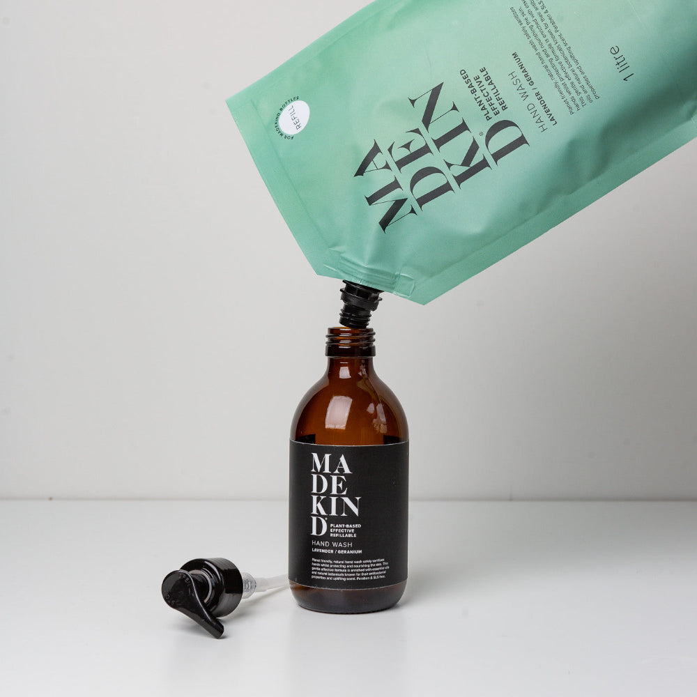 Madekind bottle being filled with a green pump from 'MADEKIND' on a white background