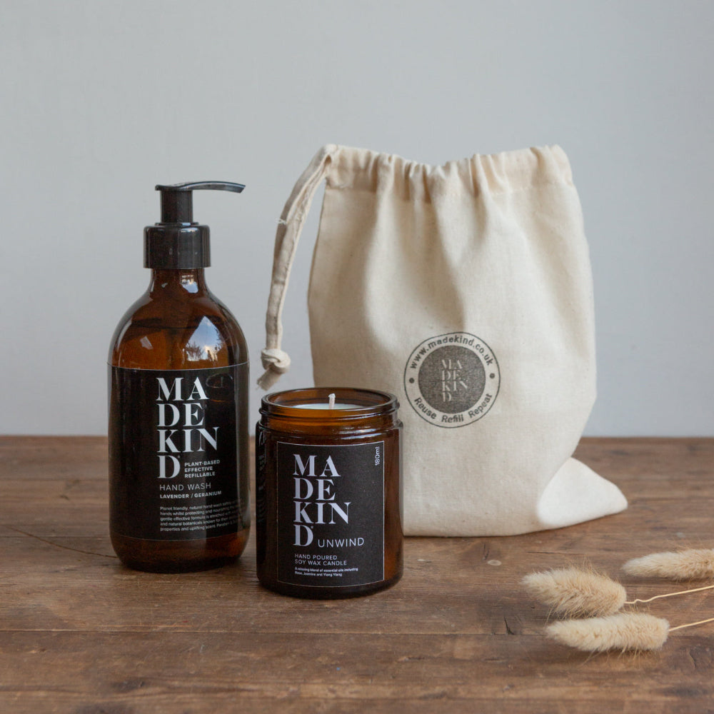 Madekind hand wash bottle, candle, and drawstring bag on a wooden surface with a neutral background.