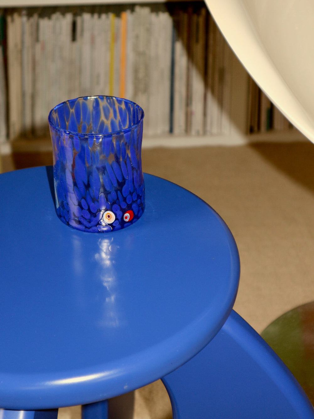 Blue glass with abstract design on a blue stool against a blurred background