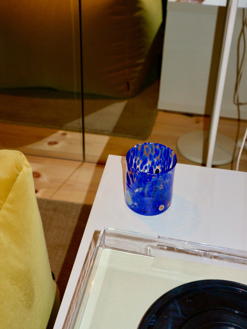 Blue Murano glass tumbler on a white table with a blurred background