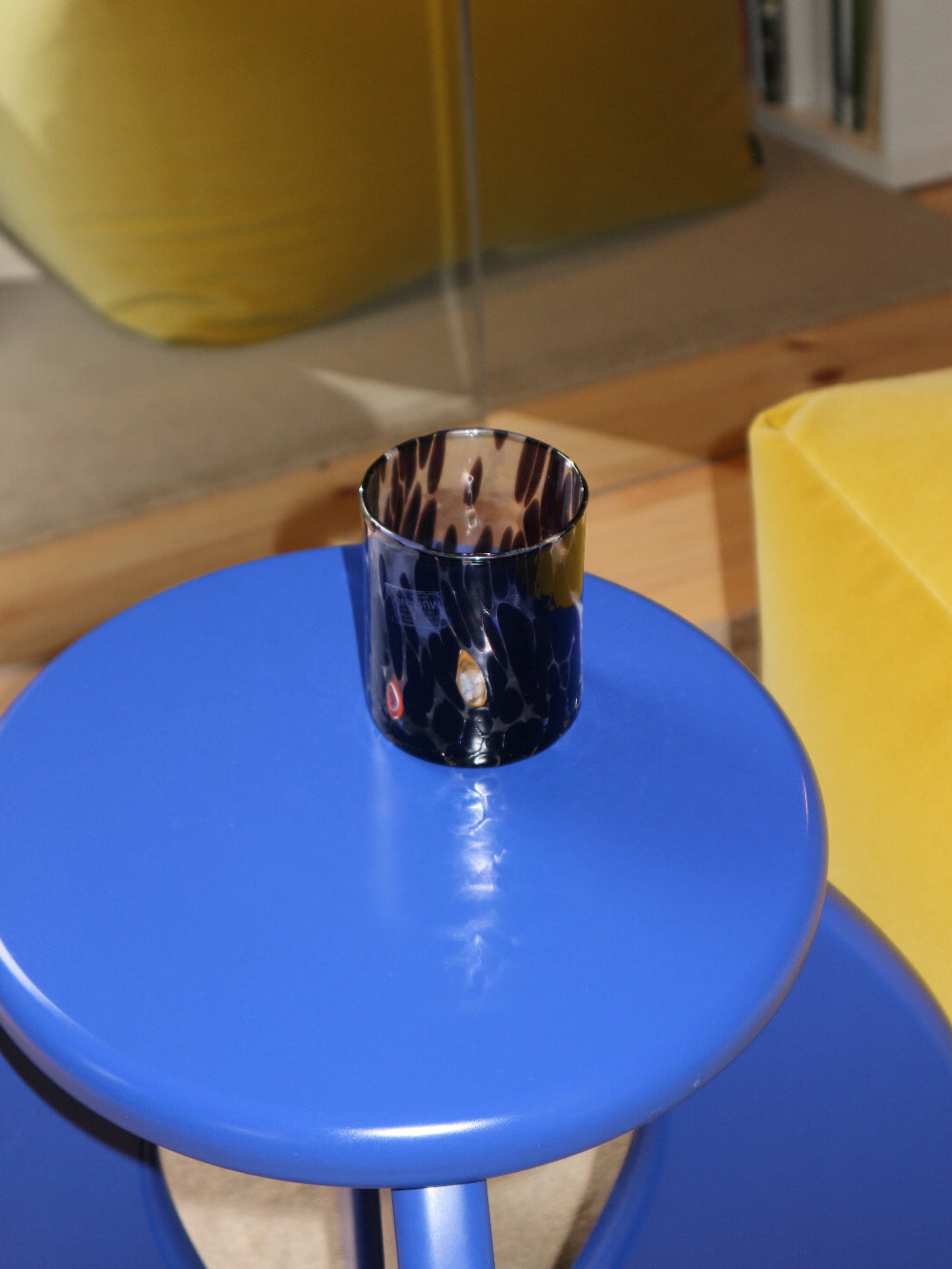 Brown glass tumbler on a blue stool with a blurred indoor background