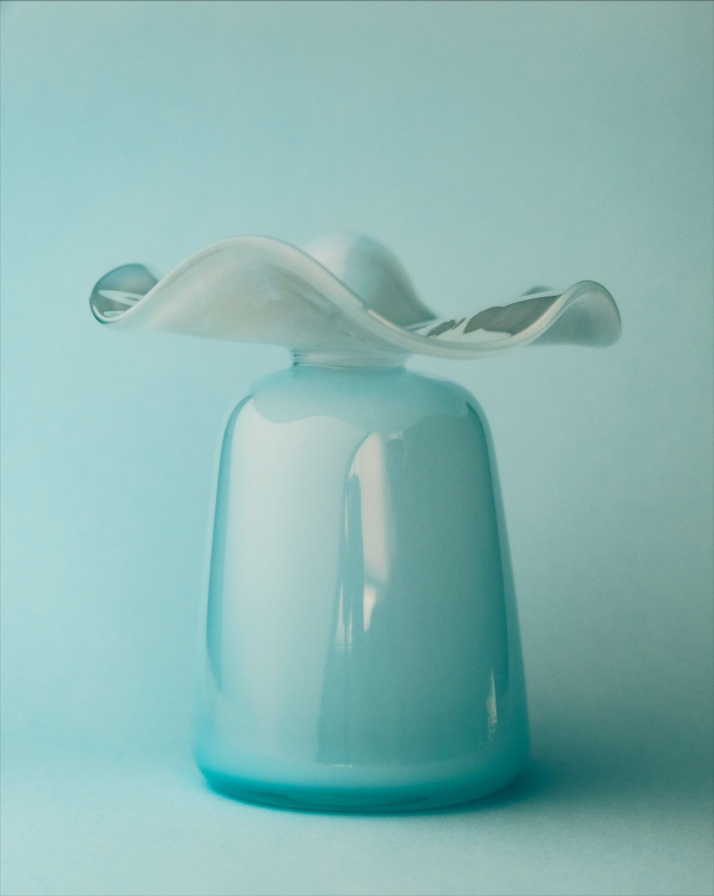 Modern glass vase with wavy design on a light blue background