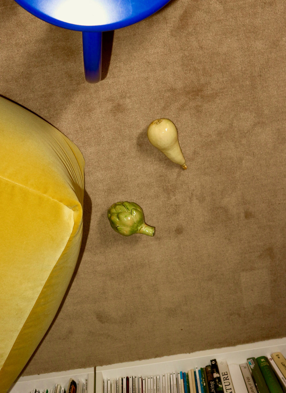 Two small vegetables on a textured surface with a blue object and yellow fabric in the foreground.