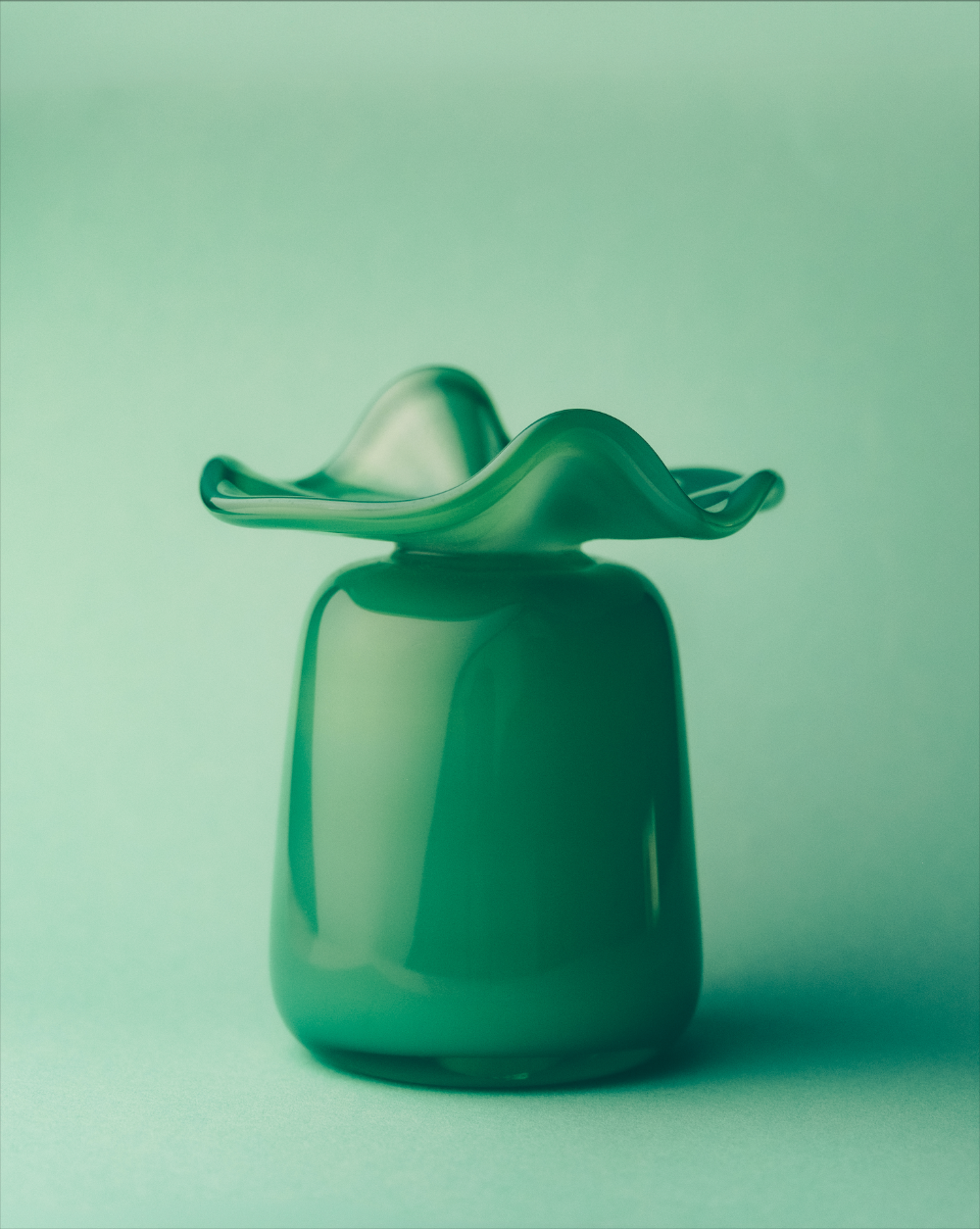 Green glass vase with unique design on a light green background