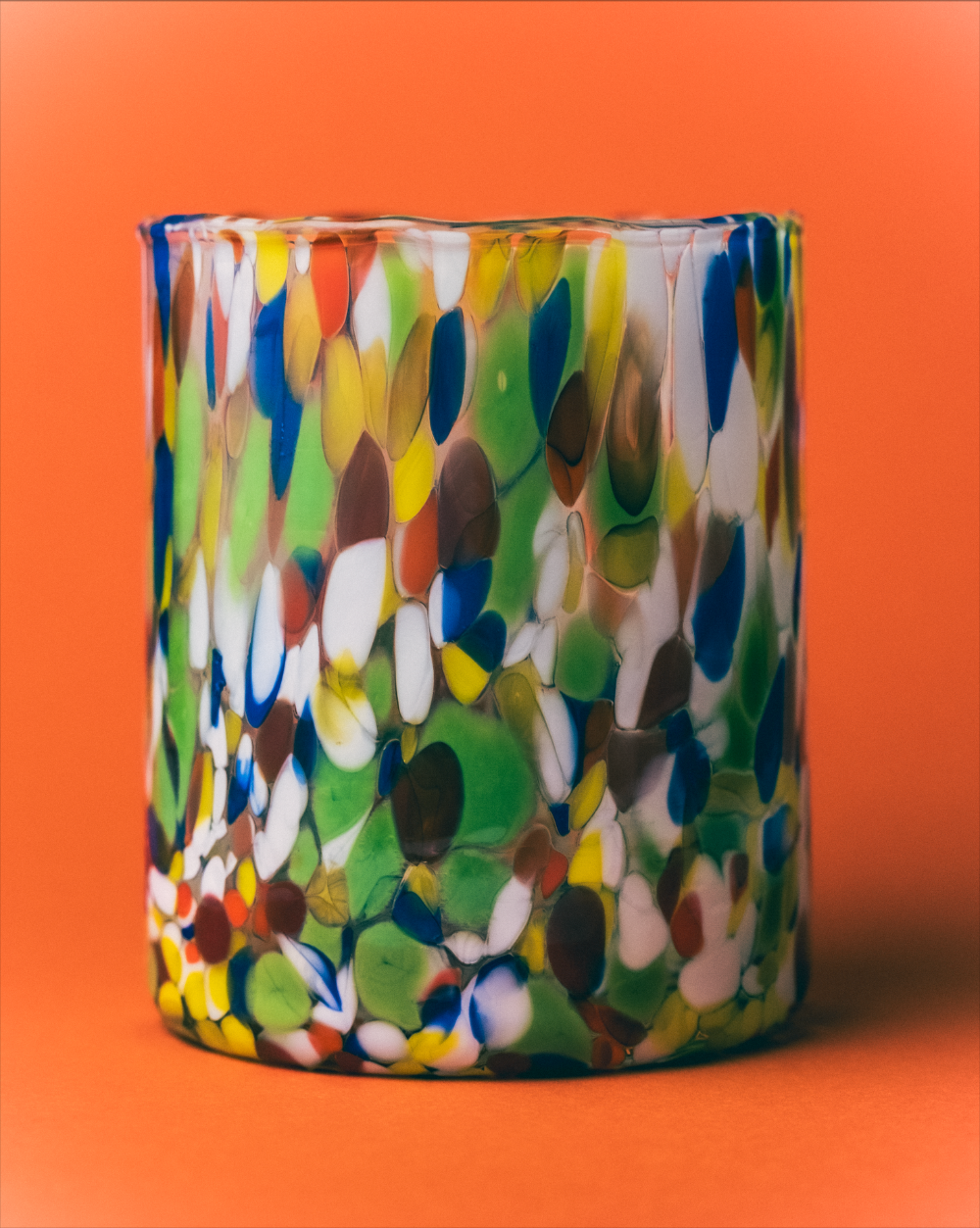 Multicolored glass tumbler on an orange background