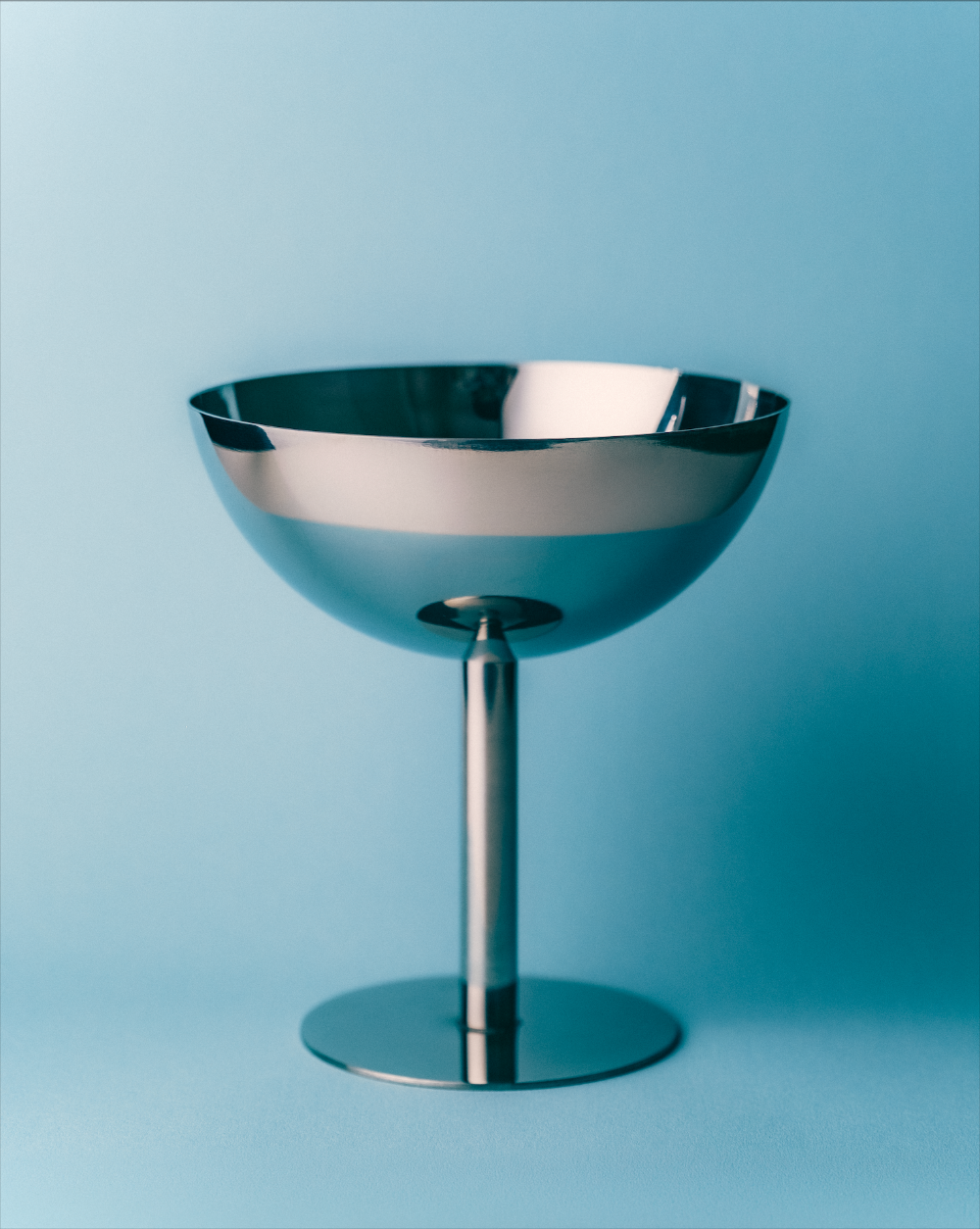 Metallic bowl on a stand against a blue background