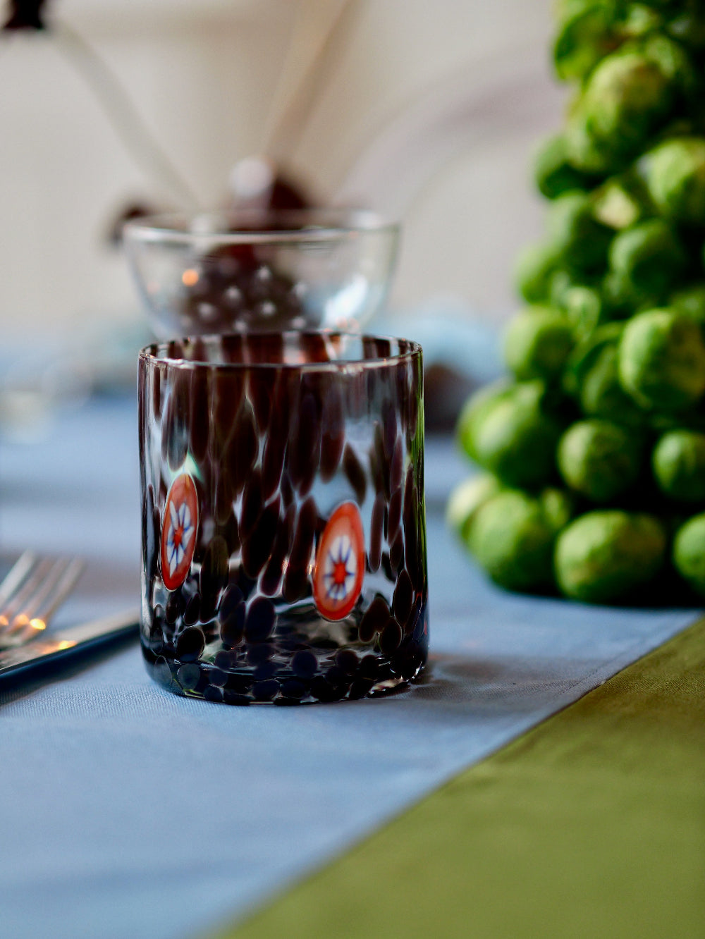 Glass with decorative design on a table with brussels sprouts
