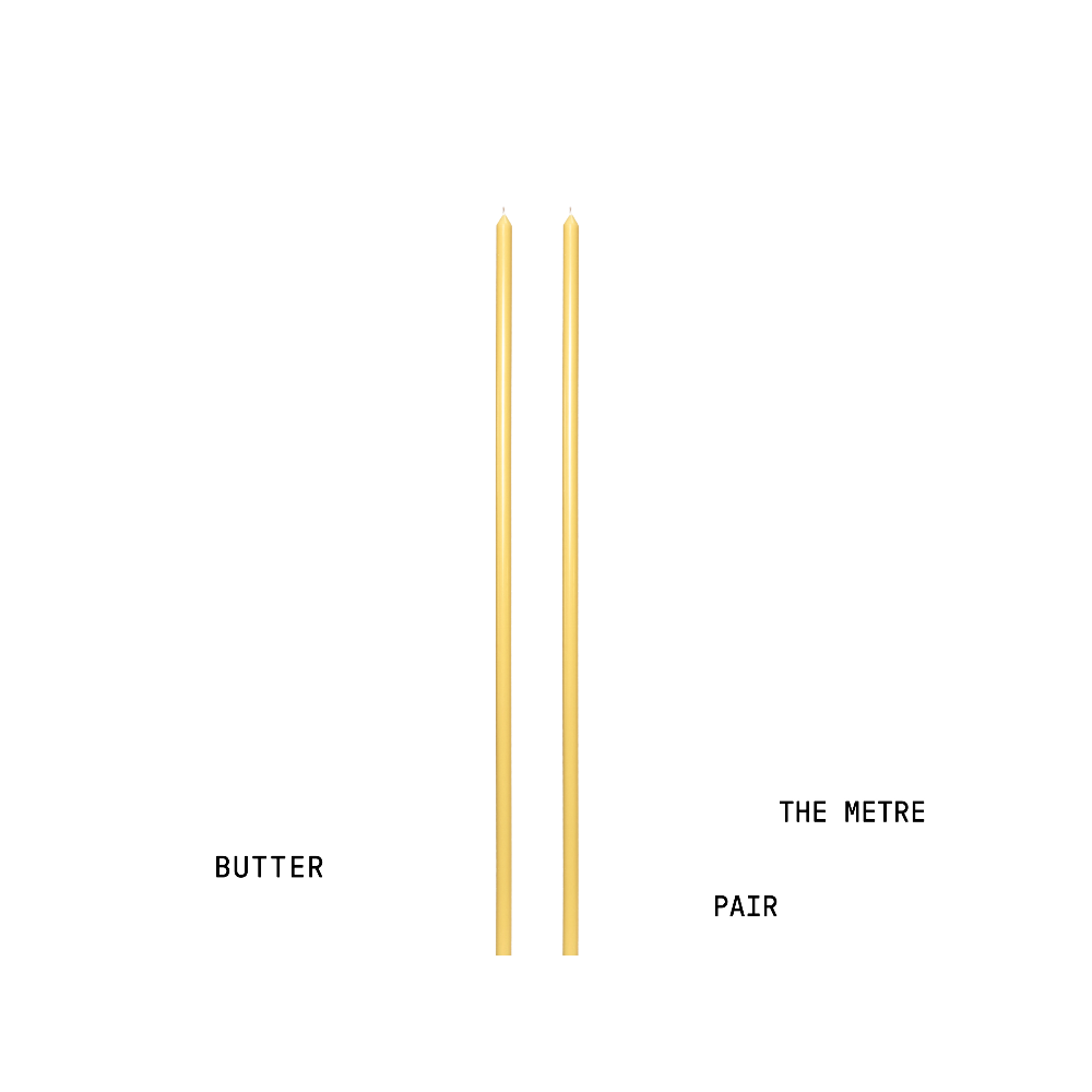 Two yellow tapered candles labelled 'Butter' and 'The Metre Pair' on a white background