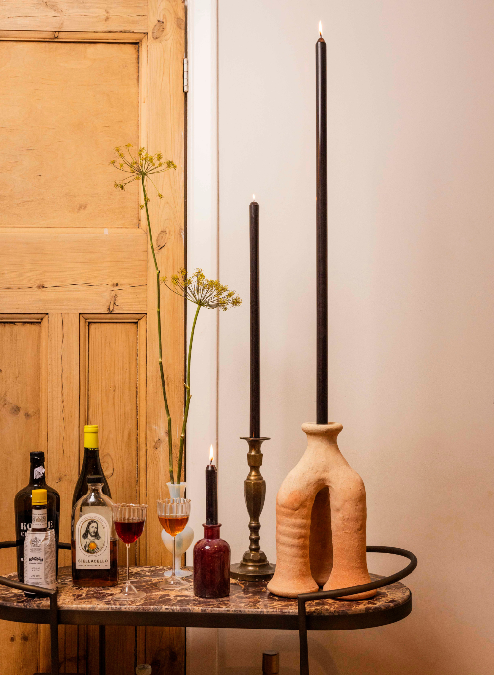 Table with wine bottles, glasses, and decorative items against a wooden panel background