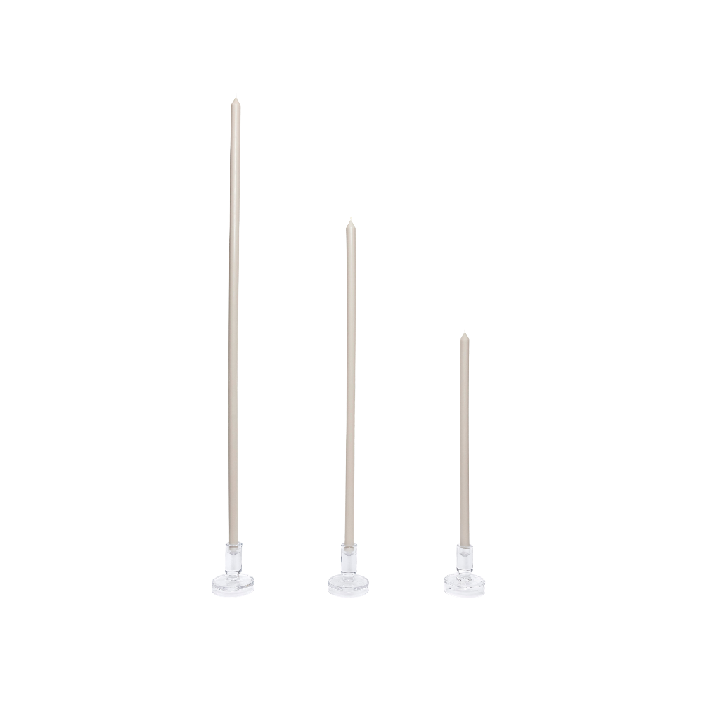 Three soft grey candles on white stands against a white background