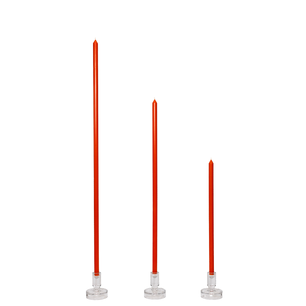 Three orange tapered candles with clear holders on a white background