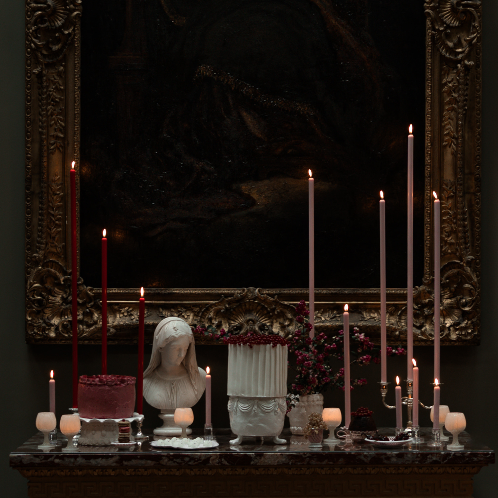 Candlelit scene with sculptures and decorative items against a dark background