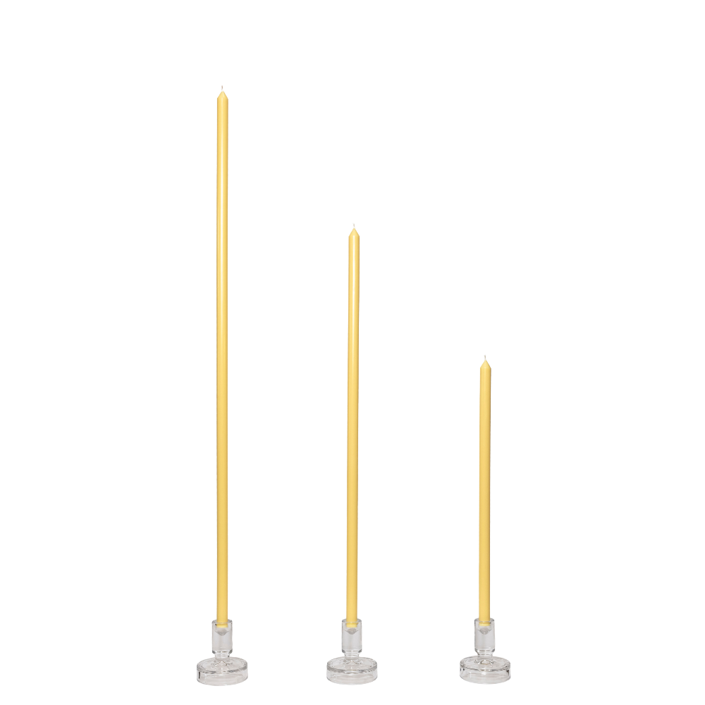 Three butter yellow candles with silver candle holders on a white background
