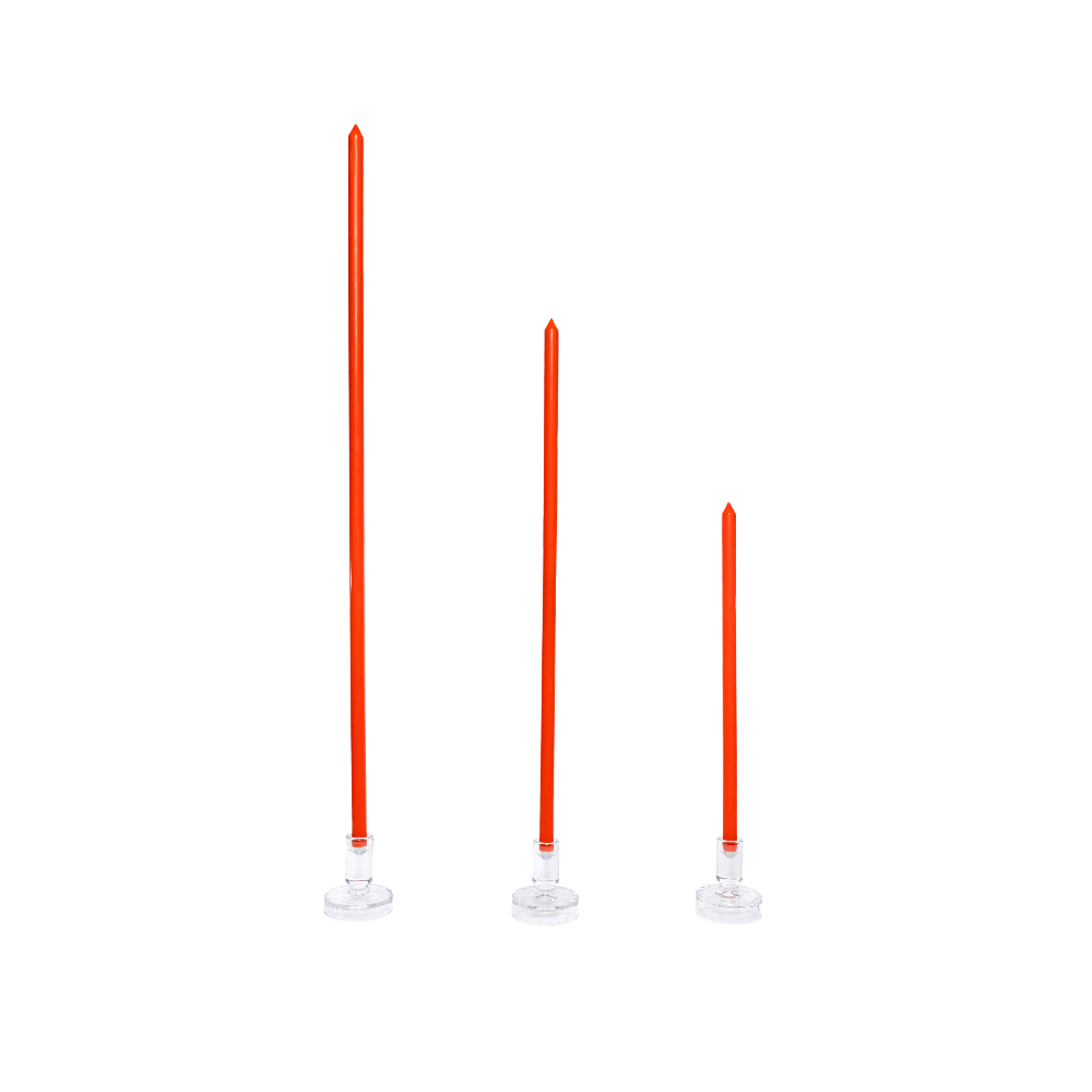 Three tomato coloured candles on white stands against a white background