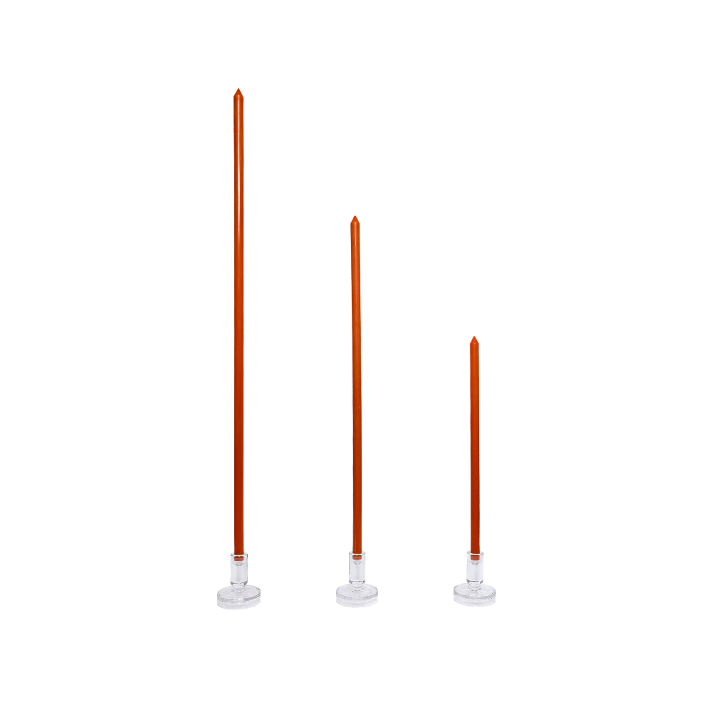 Three tall, thin candles with orange wax and white bases on a white background