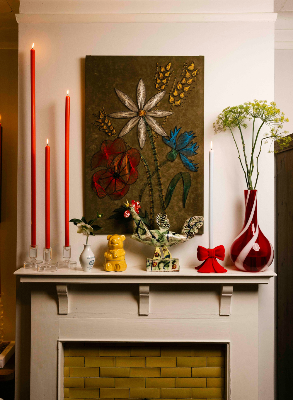 Decorative fireplace mantle with candles, artwork, and decorative items.
