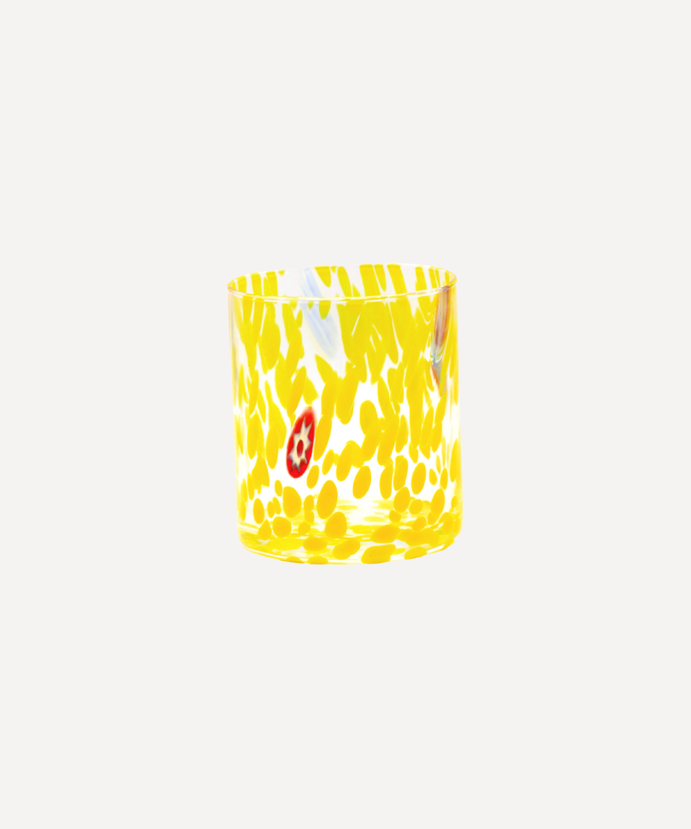 Yellow Murano glass tumbler with white abstract patterns on a white background