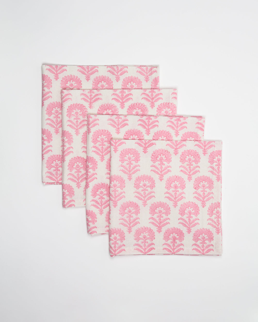 Set of four pink floral patterned napkins on a white background