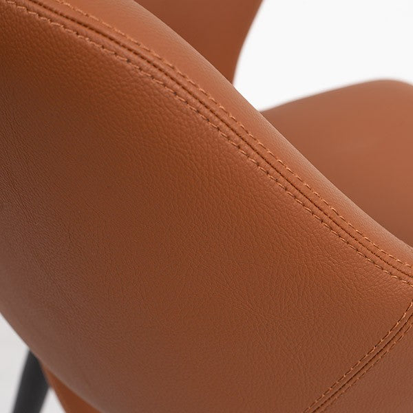 Close-up of brown faux leather dining chair with visible stitching