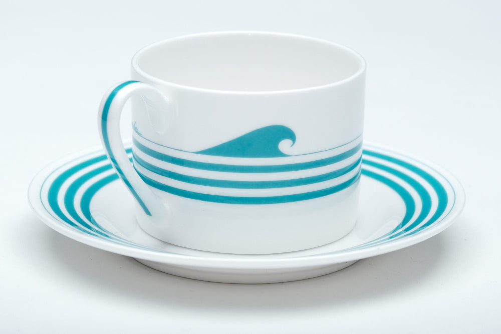 Ceramic cup and saucer with blue wave design on a white background