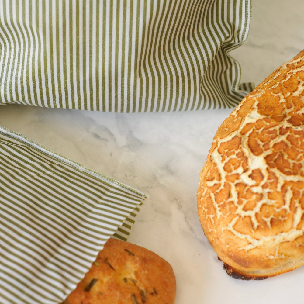 Bread on a marble surface with a green striped beeswax food bags in the background
