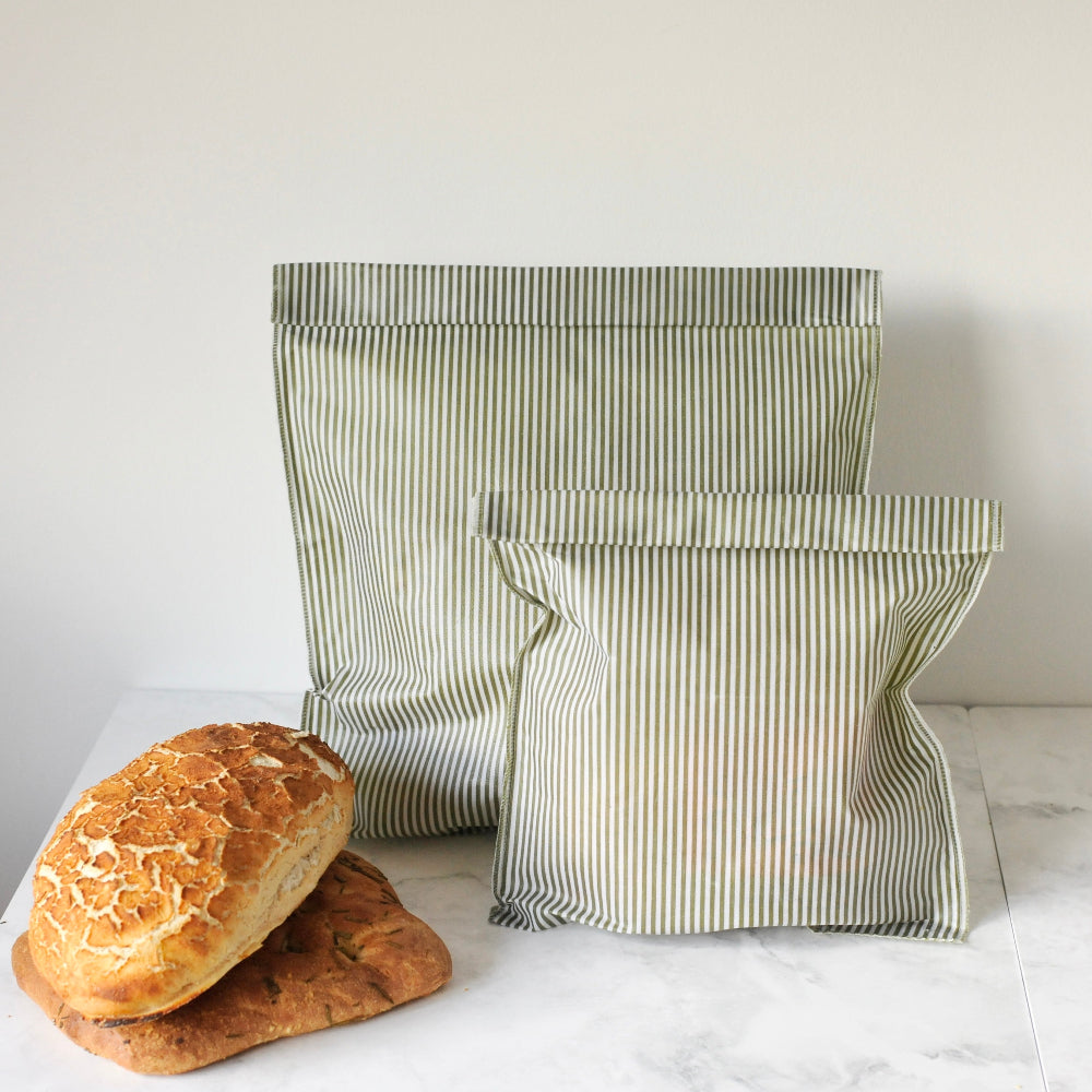 Striped beeswax food bags with bread on a white surface