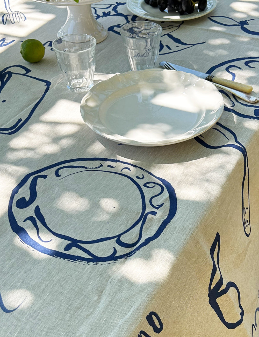 Table setting with white plates, glasses, and a decorative tablecloth featuring blue patterns.
