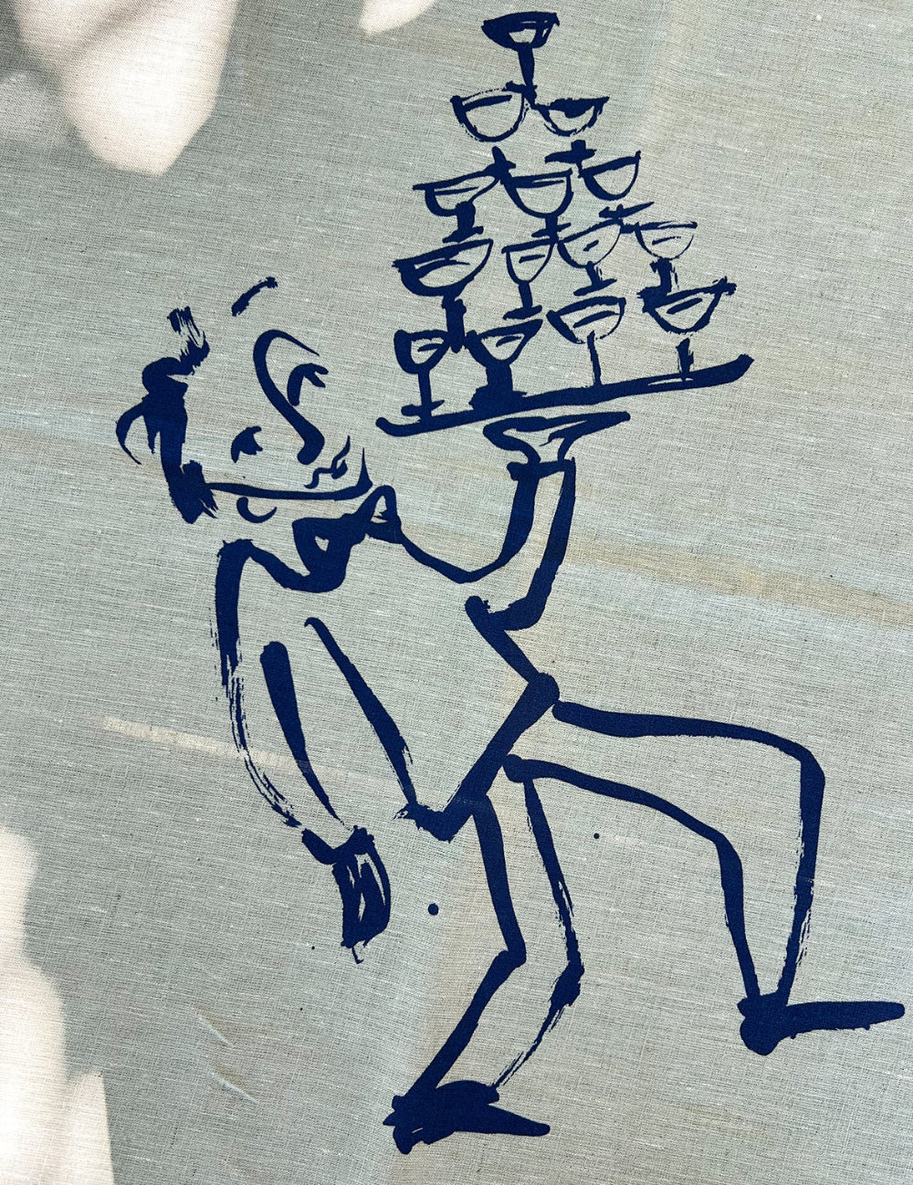 Blue ink drawing of a waiter carrying a tray with glasses on a linen tablecloth by Olivia Sewell