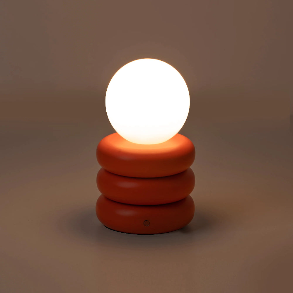 Night view of orange cordless table lamp with clear glass shade