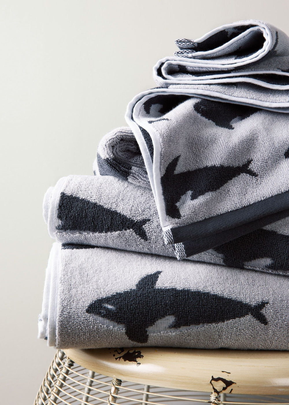 Stack of grey towels with Orca Whale patterns on a white surface