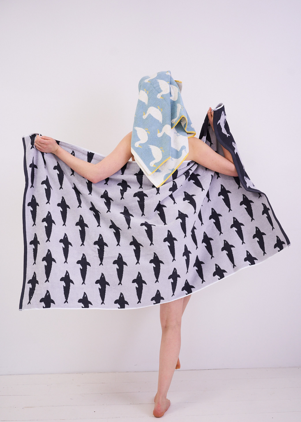 Person holding a patterned towel with Orca whale design on a white background