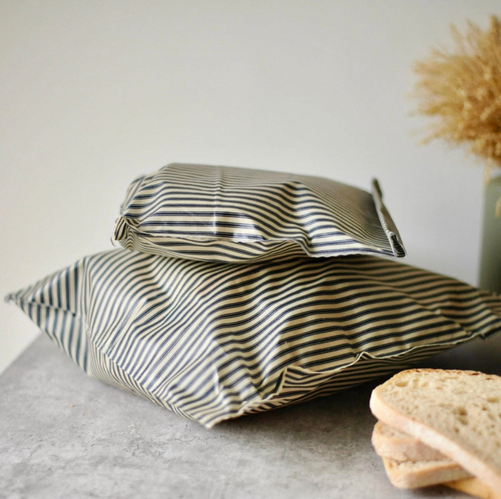 Two striped organic cotton beeswax food bags on a grey surface with a light background