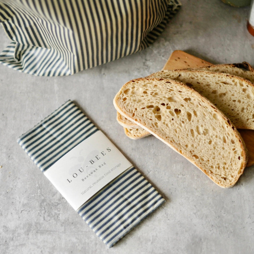 Sliced bread with a striped bread bag on a concrete surface
